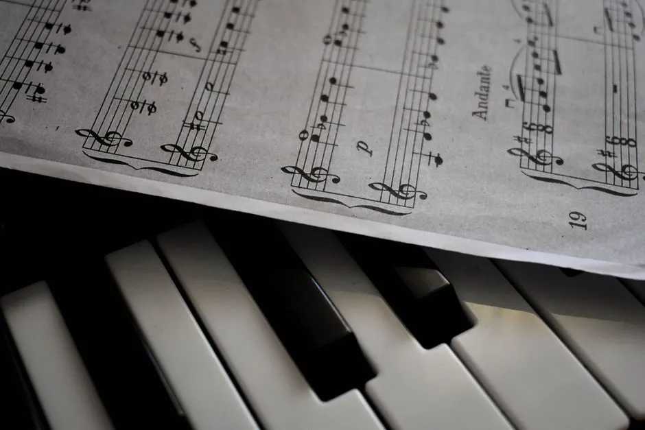 Close-up of piano keys with a sheet of musical notation resting above them