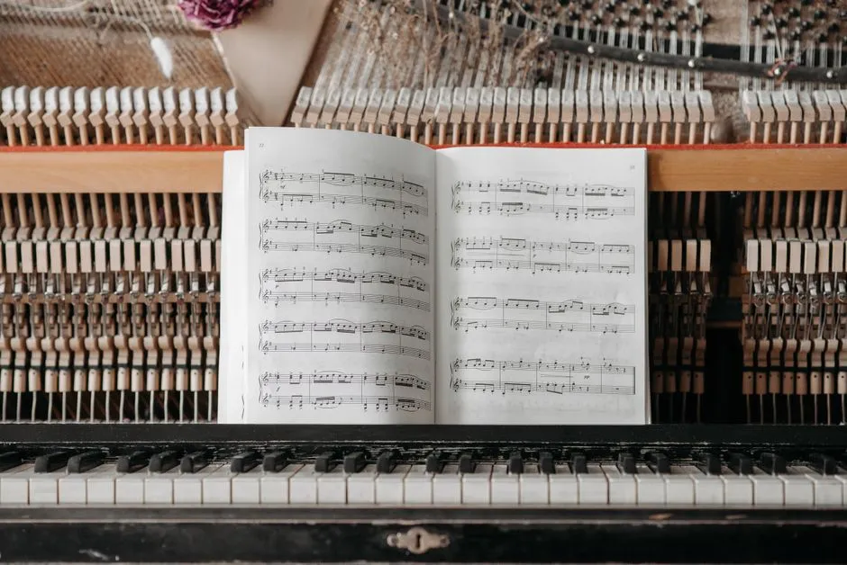 Open sheet music resting on the keys of an upright piano, with the instrument's internal hammers visible behind it